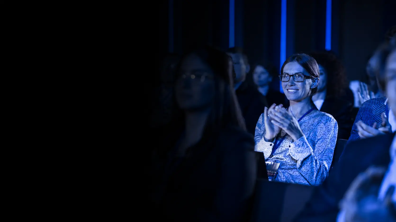 Corporate event audience applauding under professional blue event lighting by NextGen AV in Melbourne