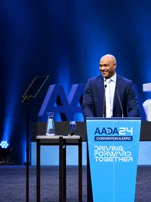 Presenter using professional conference and seminar AV, including a lectern, microphones and teleprompter.
