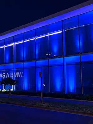 Blue-lit showroom windows and landscaped frontage at night.
