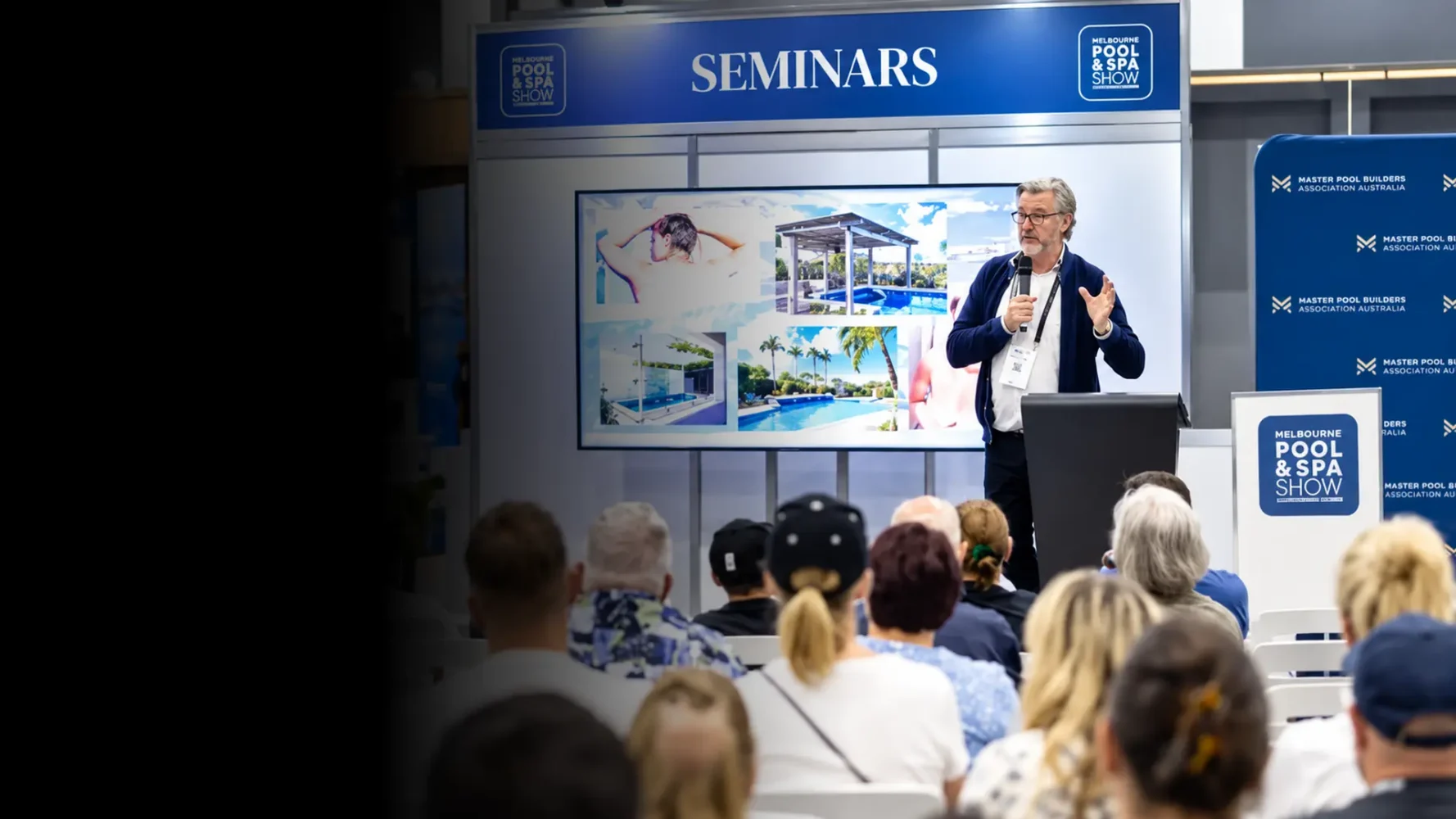 Exhibition AV hire supporting a live seminar with a presenter, large display, lectern and seated audience.