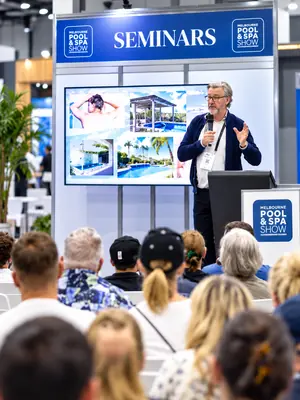 Live exhibition seminar using professional AV with a presentation screen, lectern, microphone and audience.