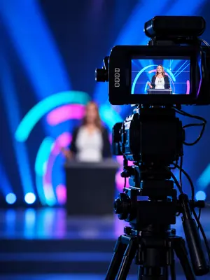 Broadcast camera and monitor capturing a presenter during a professional hybrid event livestream.