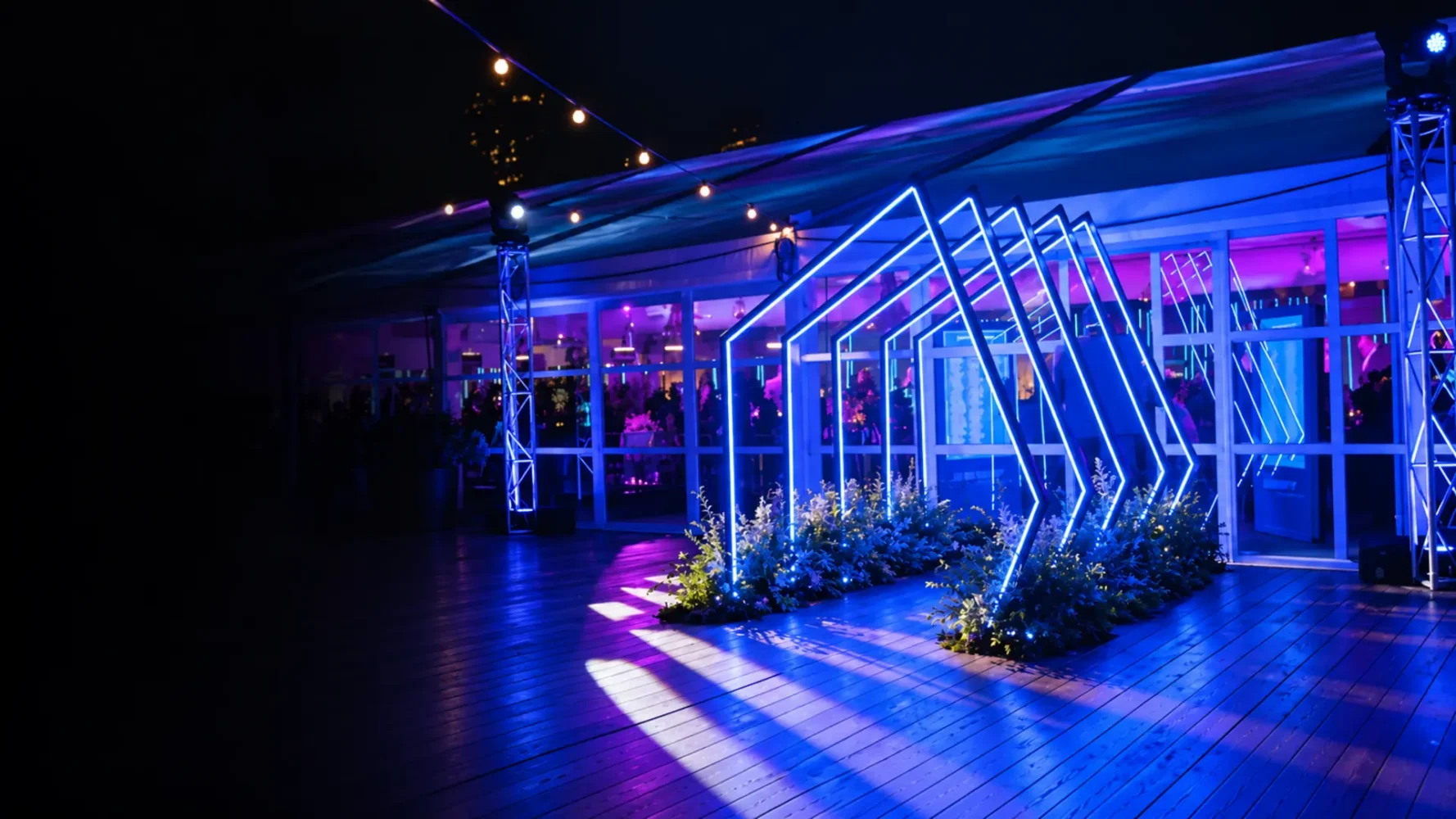 Lighting hire installation with blue-white LED entrance frames, violet venue lighting and illuminated truss towers