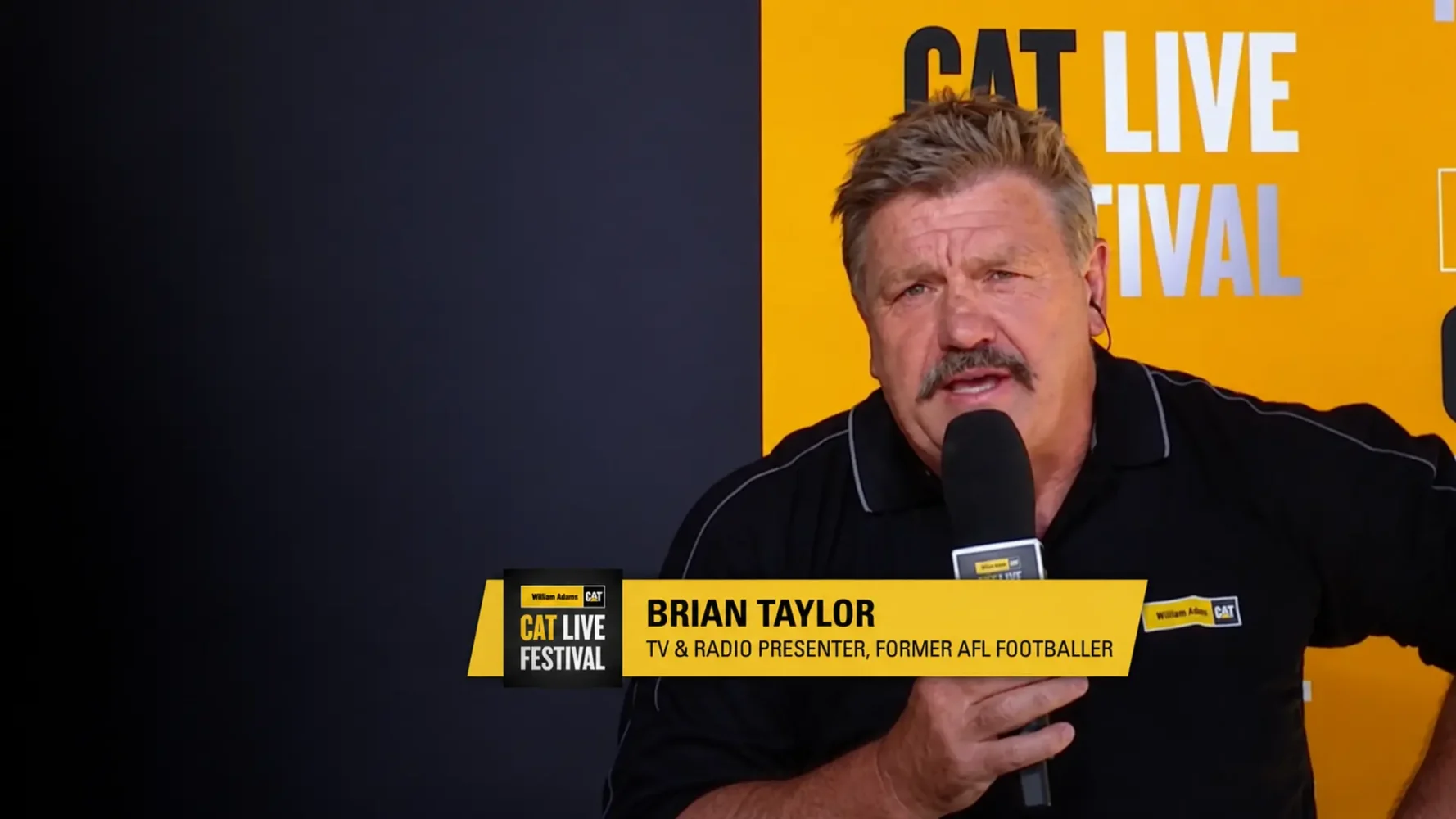 CAT Live Festival broadcast presenter holding a microphone against a yellow branded backdrop.