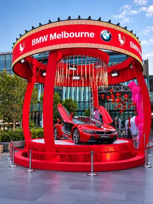 Red BMW i8 displayed beneath a branded red canopy with lanterns and decorative hanging rods.