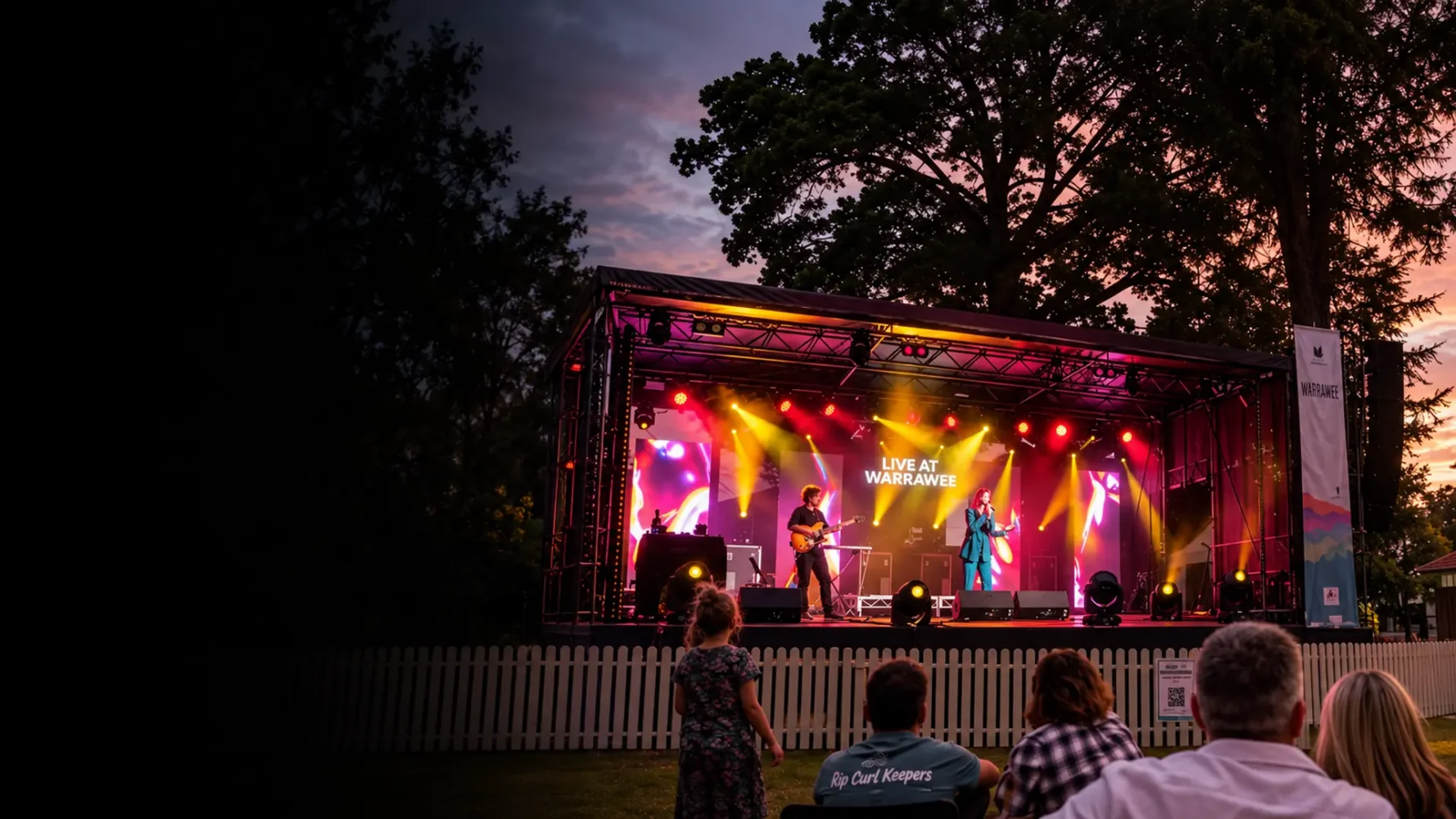 Outdoor stage package with a covered performance platform, colourful lighting and live musicians at dusk.